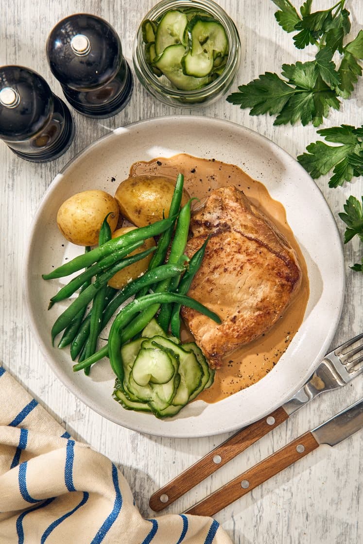 Stekt fläskkotlett med gräddsås, potatis och pressgurka