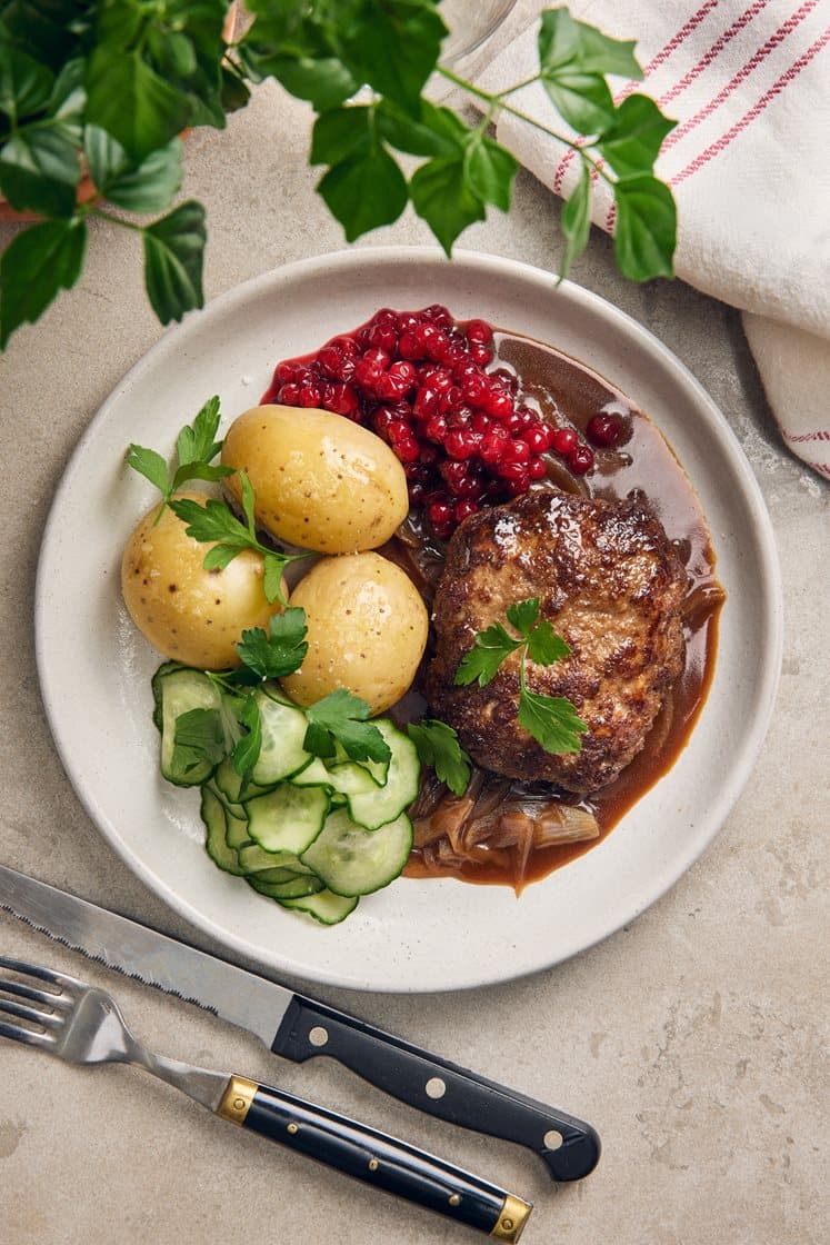 Pannbiff med löksky, pressgurka, rårörda lingon och kokt potatis